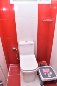a red and white bathroom with a toilet and a scale at Amsam Family Stay in Thanjāvūr