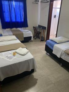 a hotel room with two beds and a table at Hotel Bee's Sorriso in Sorriso