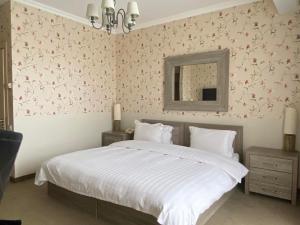 1 dormitorio con 1 cama grande y papel pintado de flores rosas en Ambassadori Kachreti Golf Resort en Kachretʼi