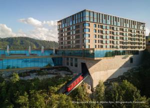 un bâtiment avec un train rouge devant lui dans l'établissement Bürgenstock Hotel & Alpine Spa, à Bürgenstock
