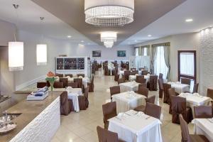 un comedor con mesas blancas y sillas marrones en Lo Scacciapensieri Hotel & Restaurant, en Monteroni di Lecce