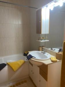 ein Badezimmer mit einem Waschbecken, einer Badewanne und einem Spiegel in der Unterkunft Casa M Falésia in Albufeira