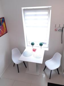 a white table and two white chairs in front of a window at Apartament Pegaz in Gniezno +5 photos