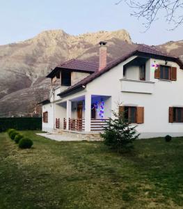 a white house with a mountain in the background at Paja Guesthouse - Camping in Bogë