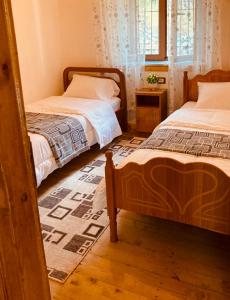 a bedroom with two beds and a rug at Paja Guesthouse - Camping in Bogë