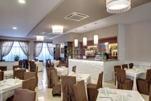 a restaurant with white tables and chairs and a bar at Lo Scacciapensieri Hotel & Restaurant in Monteroni di Lecce