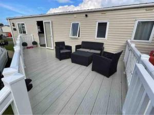 a deck with a couch and chairs on a trailer at Beautiful 3 bed Static Caravan with Snowdon views in Caernarfon in Caernarfon