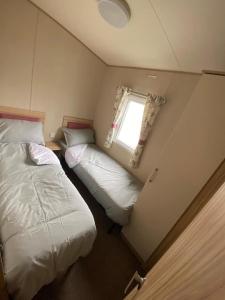a small bedroom with two beds and a window at Beautiful 3 bed Static Caravan with Snowdon views in Caernarfon in Caernarfon