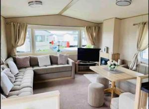 a living room with a couch and a table at Beautiful 3 bed Static Caravan with Snowdon views in Caernarfon in Caernarfon