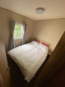 a bedroom with a white bed with a window at Beautiful 3 bed Static Caravan with Snowdon views in Caernarfon in Caernarfon