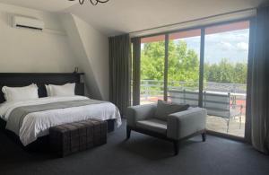 1 dormitorio con 1 cama, 1 silla y 1 ventana en Ambassadori Kachreti Golf Resort en Kachretʼi