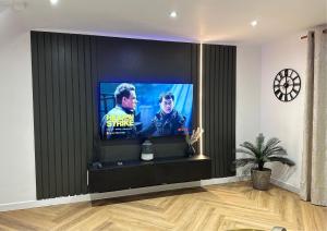 a flat screen tv in a living room at Bella-Ruiz Home for Your Perfect Staycation in London