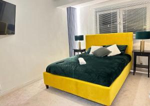 a yellow bed with a green blanket and pillows at Bella-Ruiz Home for Your Perfect Staycation in London