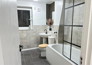 a bathroom with a toilet and a sink and a tub at Bella-Ruiz Home for Your Perfect Staycation in London