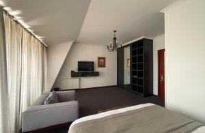 Kachretʼi的住宿－Ambassadori Kachreti Golf Resort，一间卧室配有一张床、一张沙发和一台电视