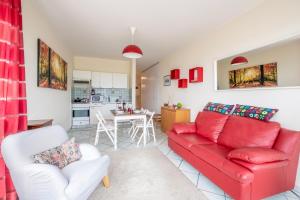 een woonkamer met een rode bank en een keuken bij Pazzallo Panoramica - Happy Rentals in Lugano