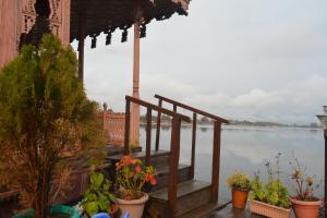 a porch with plants on it next to the water at Golden Flower Heritage Houseboat in Srinagar
