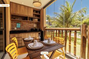 a dining room with a table and chairs and a balcony at Lindo térreo ao lado da piscina no VG Sun Cumbuco in Cumbuco