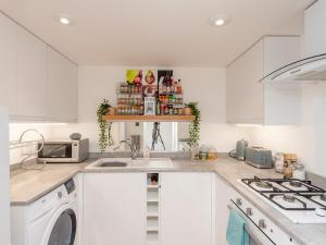 a white kitchen with a sink and a washing machine at Pass the Keys Hidden Gem Near Roundhay Park in Leeds