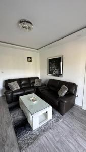 Sala de estar con sofá de cuero negro y mesa de centro en Vila Jovanka, en Tivat
