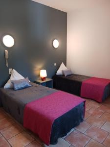 a room with two beds with pink sheets at Hotel Du Lac in Château-Arnoux-Saint-Auban