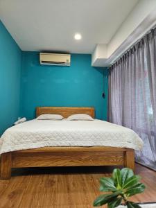 a bedroom with a bed and a blue wall at Green Cocoon in Ho Chi Minh City