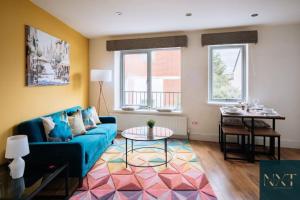 Apartment in Central Watford في واتفورد: غرفة معيشة مع أريكة زرقاء وطاولة