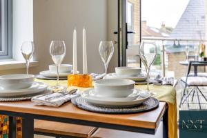 Apartment in Central Watford في واتفورد: طاولة غرفة الطعام مع الأطباق وكؤوس النبيذ