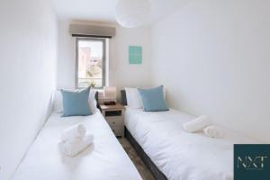 Apartment in Central Watford في واتفورد: سريرين في غرفة مع وسائد زرقاء وبيضاء