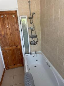 - Baño con bañera y puerta en Lovely 2 bedroom Apartment with Free Parking, en Borrowash