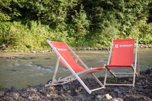 two lawn chairs sitting next to a river at Lawendowy Staw in Cisna