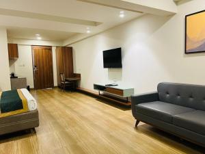 a room with a couch and a desk and a television at The Lemon Grass Hotel in Gandhinagar