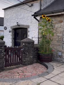 ein Haus mit einem Holztor und einer Tür mit Sonnenblume in der Unterkunft Old Nursery in Coity