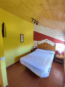 1 dormitorio con 1 cama y pared amarilla y roja en Casa Rural Los Riscos de Gredos, en Hoyos de Miguel Muñoz