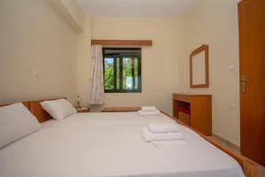 a bedroom with a large white bed with towels on it at Xenios Zeus Apartments in Kissamos