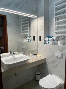 a white bathroom with a sink and a toilet at Apartamenty Browar Luxury Old Town Poznań Check In 24h in Poznań