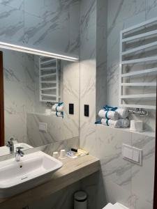 Baño blanco con lavabo y espejo en Apartamenty Browar Luxury Old Town Poznań Check In 24h, en Poznan