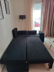 a black couch in a living room with a window at 3 min from central station No2 private free parking in Thessaloniki