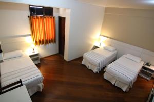 Habitación con 2 camas y ventana con cortinas de color naranja. en Samba Betim en Betim