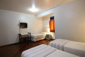 um quarto de hotel com duas camas e uma televisão em Samba Betim em Betim