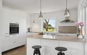 una cocina con armarios blancos y una barra con taburetes en Awesome Home In Bandholm With House Sea View en Bandholm