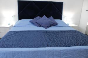 - un grand lit bleu avec deux oreillers dans l'établissement LA LANTERNA DI ANGELO, à Gênes
