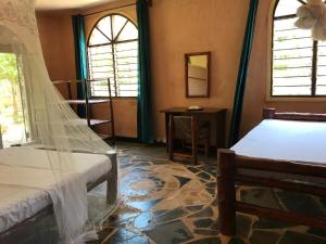een slaapkamer met een bed en een tafel en ramen bij Room in Villa - 38m2 Turtle Suite in a 560 m2 Villa, Indian Ocean View in Shimoni