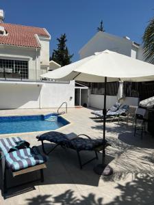 利馬索爾的住宿－Villa Sawa by Ezoria Villas，游泳池旁的天井配有椅子和遮阳伞。