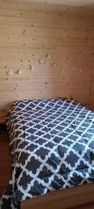 a bed with a black and white comforter in a room at Les Hauts du Roux in Abriès