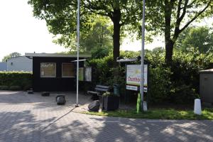 una parada de autobús con un banco y un cartel en Holiday park Duinhoeve en Udenhout