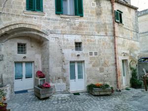 un antiguo edificio de piedra con persianas verdes y flores en S@sso Matto, en Matera