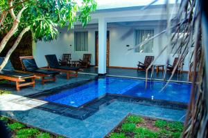 a swimming pool with chairs and a house at Sigiriya Water Cottage in Sigiriya