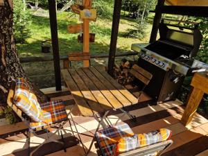 einem Picknicktisch und einem Grill und einem Stuhl auf einer Terrasse in der Unterkunft Glamping Štôla- Symbioza in Štôla