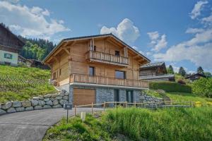 a wooden house with a balcony on a hill at Magnifique Chalet neuf 8 pers, 800 m télécabine Princesse Megeve in Combloux